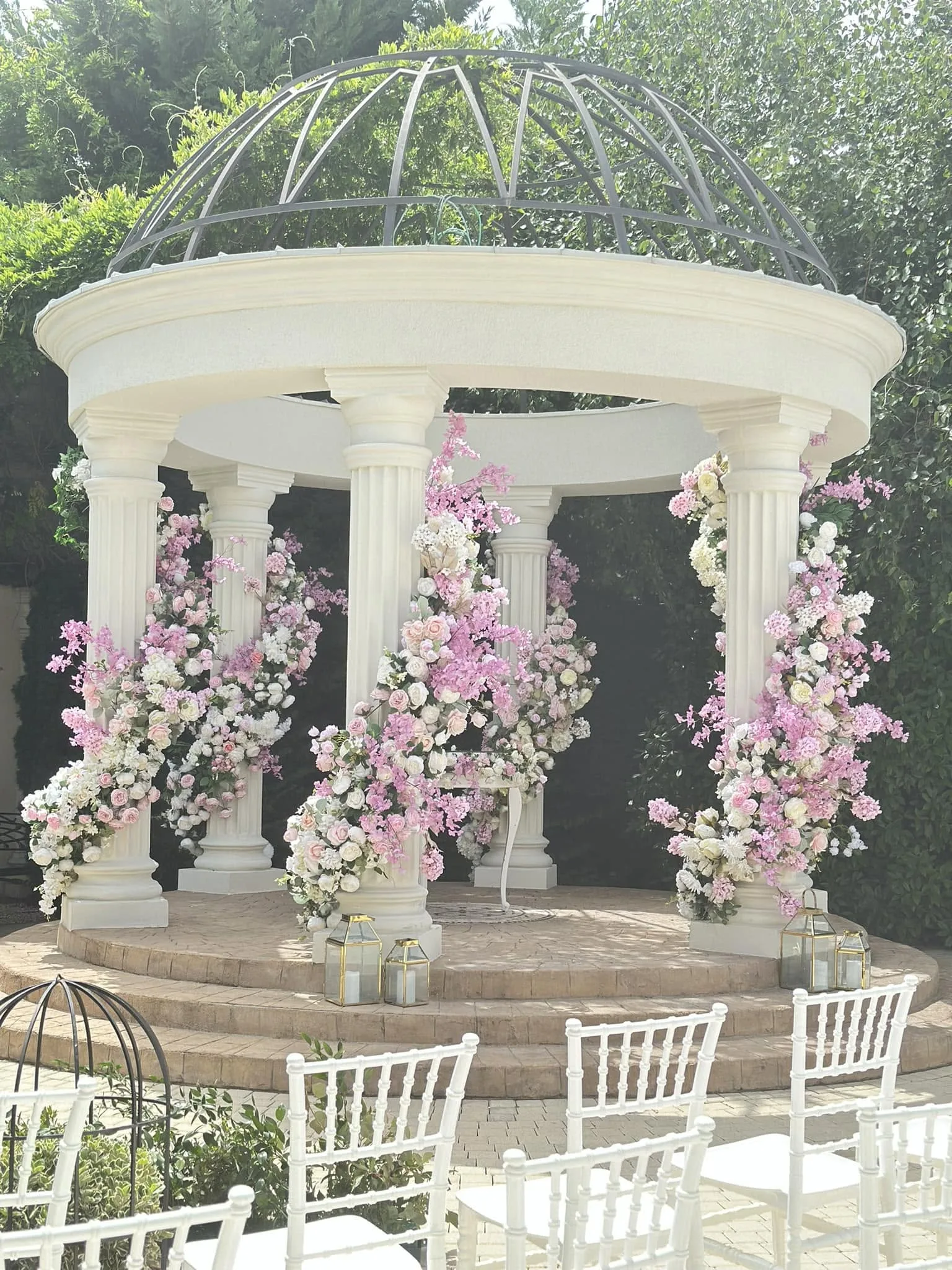 Gazebo alb îmbrăcat integral în flori roz și albe, decor ceremonie exterior