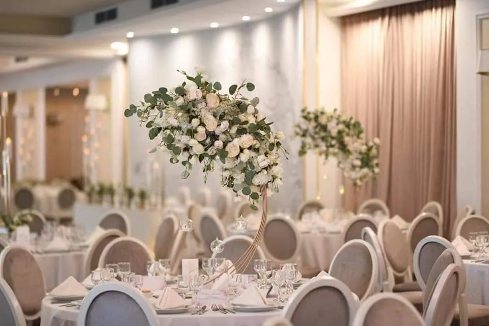 Aranjament floral asimetric suspendat deasupra mesei, sală de banchet